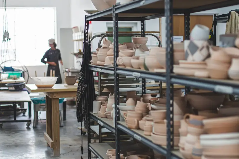 A potter among shelves of fired pots in the Lygon Street studio