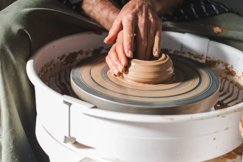 Hands centring clay on a pottery wheel