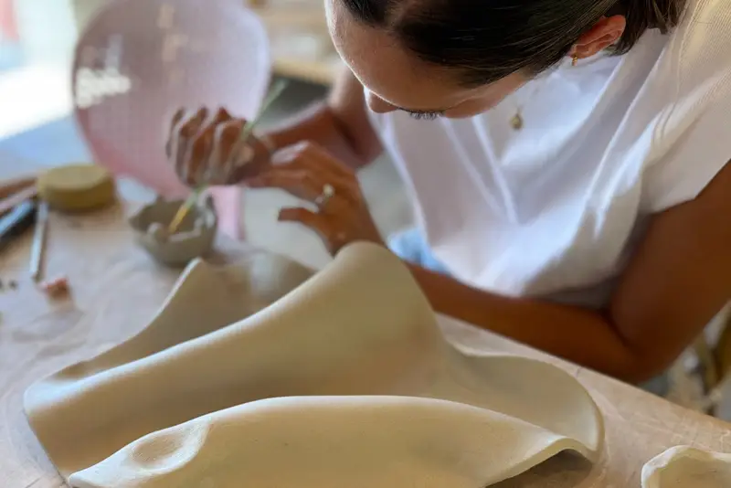 A student shaping a slab of clay into a wall vase