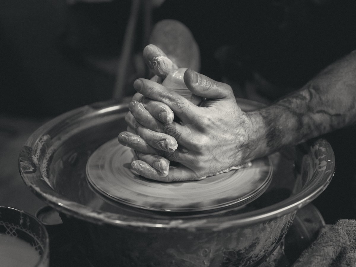 Hands shaping clay on a potter's wheel