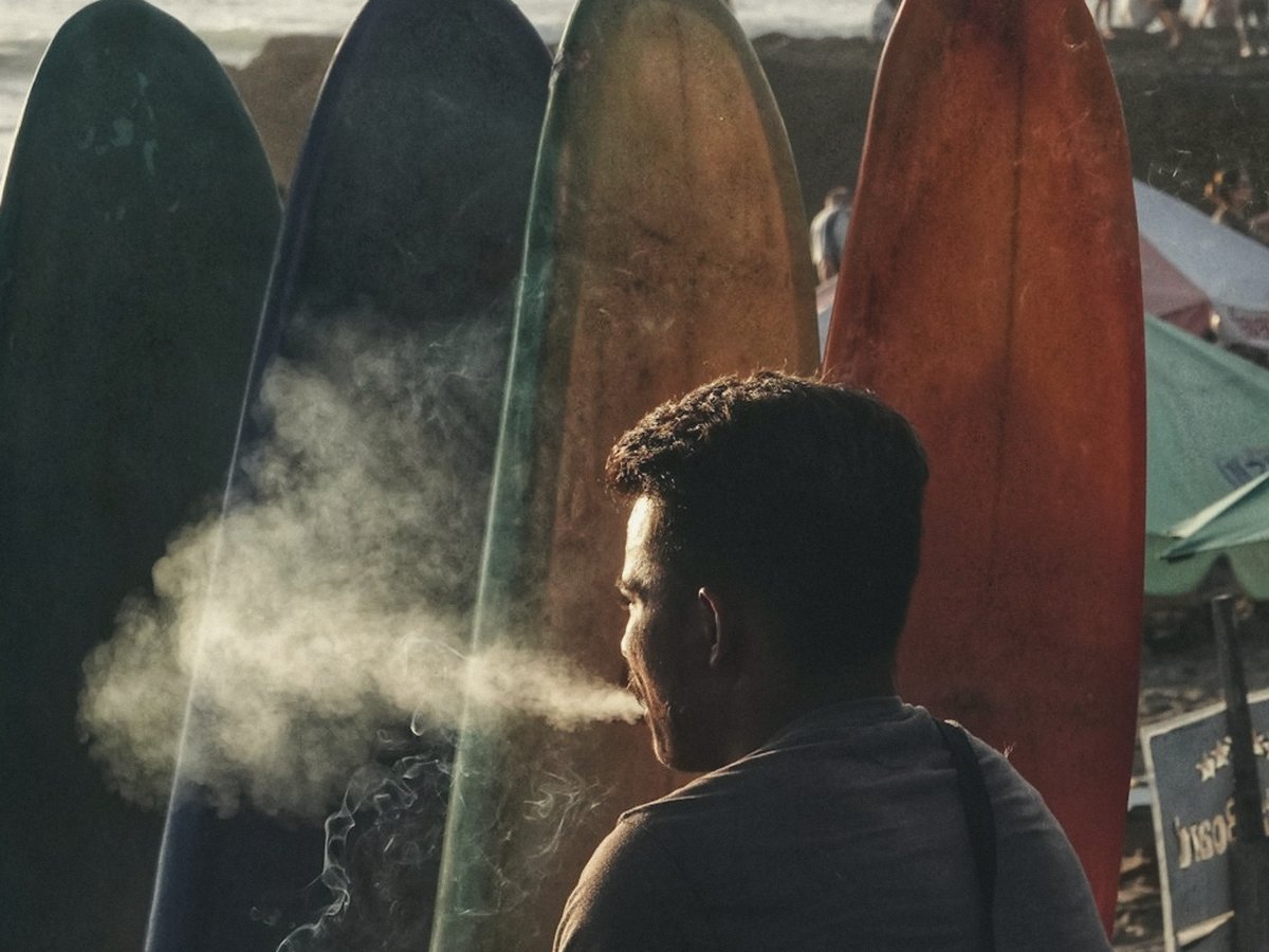 Colourful surfboards lined up on a Bali beach at golden hour, ocean and beachgoers in the background