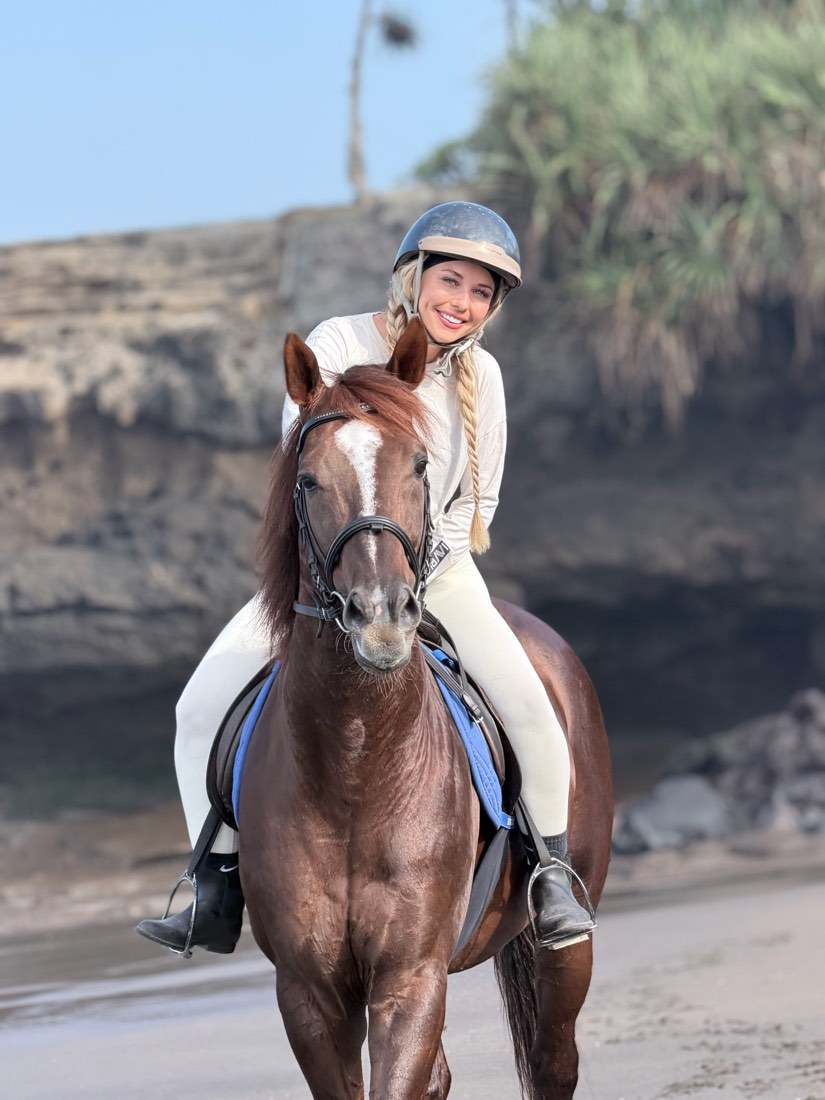 Horse and rider on the beach with rice fields behind, Salty Cowboy Bali
